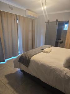 a bedroom with a large white bed with blue lights at Cozy 1 Bedroom Cottage in Piet Retief
