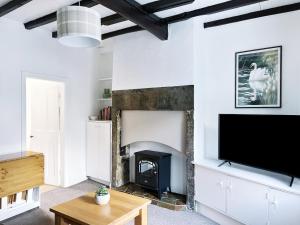 a living room with a fireplace and a flat screen tv at The Willow Nook in Pateley Bridge