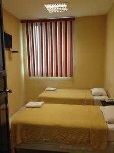 two beds in a room with a window at Hotel Moreno in Coatzacoalcos