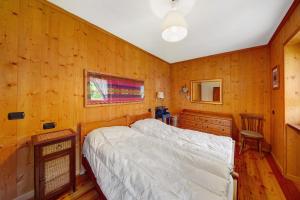 een slaapkamer met een bed en een houten wand bij Appartamento Serdes Big C2 in San Vito di Cadore