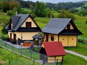 una casa con techo rojo con un parque infantil en Domki Górski Klimat, en Białka Tatrzanska