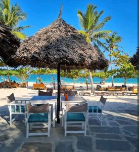 a table with a straw umbrella on the beach at Diani Studio with 3 Pools & Balcony in Diani Beach