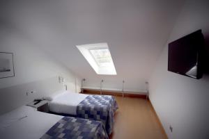 een slaapkamer met 2 bedden en een dakraam bij Apartamentos Jauregui in Hondarribia