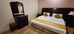 a bedroom with a bed with a dresser and a mirror at شقق حلا ثلاثه للشقق المخدومه in Al Qurayyat