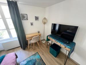 a living room with a television and a table with a desk at Montbel'appart-Le duplex jardin terrasse in Montbéliard