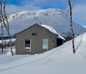 un edificio con una montaña cubierta de nieve en el fondo en Cahkal Villa, en Kilpisjärvi