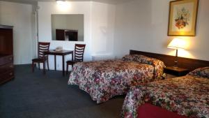 a hotel room with two beds and a table and chairs at Essex House Motel in Littleton