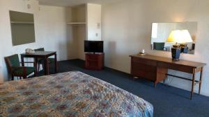 a hotel room with a bed and a desk and a mirror at Essex House Motel in Littleton