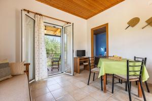 a living room with a table and chairs and a television at Nemorosa Holiday Houses in Méson Yerakaríon