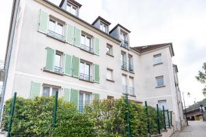 a white building with green shutters on it at Cosy T2 à 100m de la Gare, parking gratuit, WiFi Fibre pour 4 personnes in Saint-Cyr-lʼÉcole