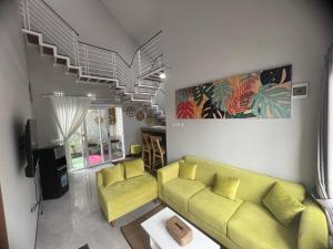 a living room with a yellow couch and a staircase at Smooth Villas in Wonosobo