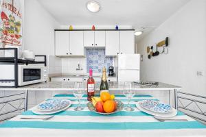 a kitchen with a table with a bowl of fruit and wine bottles at Holiday Dream Maspalomas in Maspalomas
