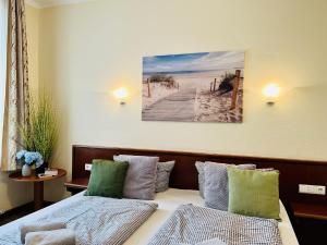 Ferienwohnung Strandlust in der Villa Seeadler Binz في بينز: غرفة نوم مع سرير مع وسائد خضراء ورمادية