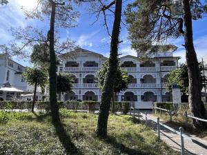 Ferienwohnung Strandlust in der Villa Seeadler Binz في بينز: مبنى ابيض كبير مع اشجار في المقدمة