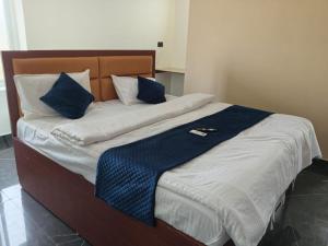 a bed with blue and white pillows on it at Aparna Hotel in Bhogāpuram