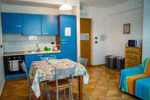 a kitchen with blue cabinets and a table with chairs at Le Tartarughe Aparthotel in Letojanni
