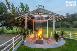 a pergola with a fire in a yard at StayVista at Kailaasa with Bonfire, Pool and Al-fresco in Suntikoppa