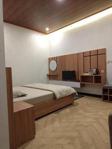 a bedroom with a bed and a television in it at Better House & Cabin Dieng in Diyeng