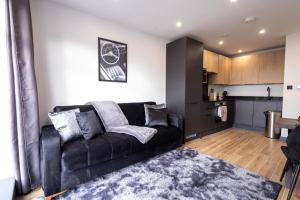 a living room with a black couch and a kitchen at Brand-New Borehamwood 1-Bed, 1-Bath Flat in Borehamwood