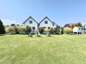 two green chairs in a yard in front of a house at Domki Kalipso in Sarbinowo