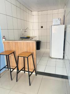 a kitchen with two stools and a refrigerator at Apartamento Boulevard in Feira de Santana +5 photos