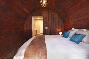 a large wooden room with a large bed with blue pillows at Hotel De Vrouwe van Stavoren in Stavoren