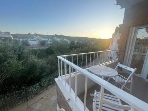 a balcony with two chairs and a table and the sunset at Mirador al puente del río Genil in Puente-Genil