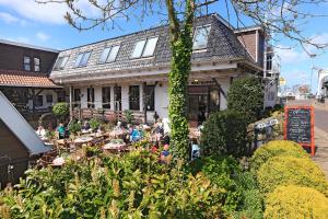 een groep mensen die aan tafels buiten een gebouw zitten bij Hotel De Vrouwe van Stavoren in Stavoren