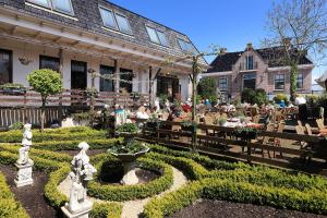 a group of people sitting at tables in a garden at Hotel De Vrouwe van Stavoren in Stavoren