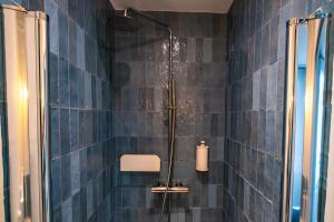 baño con paredes de azulejos azules y ducha. en 4 Guest - Hausmanian Flat Arc de Triomph, en París