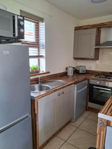 a kitchen with a sink and a refrigerator at Ulster Cottages 4 miles From Portrush Bushmills Coleraine and Ballymoney in Bushmills
