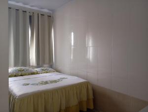a bedroom with a bed with a yellow bedspread and a window at Kit pequeno espaco popular in Riacho Fundo