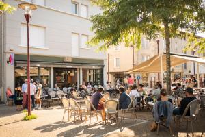 a group of people sitting at tables outside a store at Appart'hôtel Le Corot - Accès Autonome - Saint-Junien Centre in Saint-Junien +49 photos
