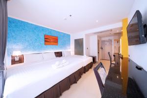 a hotel room with a large white bed and a tv at Royal Prince Resort Pattaya in Pattaya South