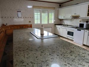 a kitchen with white cabinets and a marble counter top at Casa Pucho in Barreiros