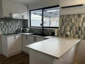 a kitchen with white cabinets and a large window at Teresa Ct in Rye +10 photos