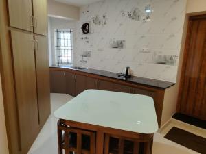a white kitchen with a counter and a stool at The Pearl Residency 2BHK 3BHK Apartments in Ooty +12 photos