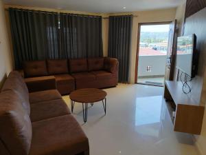 a living room with a brown couch and a table at The Pearl Residency 2BHK 3BHK Apartments in Ooty