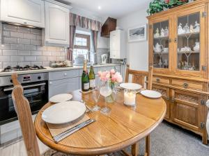 eine Küche mit einem Holztisch mit Tellern und Blumen in der Unterkunft Rose Cottage in Hartland + 15 Fotos