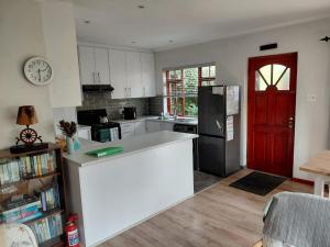 a kitchen with a white counter and a red door at Ballykeep Cottage, Constantia in Constantia