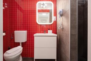 a bathroom with a toilet and a red tiled wall at R10 - Boutique Apartments, Best location by BQA in Budapest +16 photos