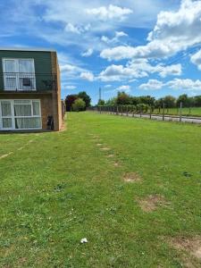 a house with a grass field next to a building at great holidays hemsby in Hemsby