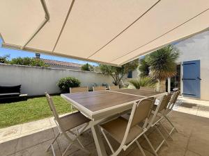 drewniany stół i krzesła pod dużym parasolem w obiekcie Maison neuve 8 pers. avec terrasse, 600m de la plage, La Cotinière, Saint-Pierre-d'Oléron - FR-1-246A-185 w mieście Saint-Pierre-dʼOléron