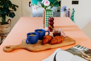 a wooden tray with croissants and two cups of coffee at Bumblebee Cabin met privé sauna & vuurplaats in Diessen
