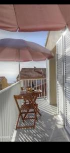 a wooden table with an umbrella on a balcony at Idéal emplacement Cargese 3 in Cargèse