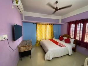 Un dormitorio con dos camas y un ventilador de techo. en Hotel O Siva Karthika, en Trivandrum