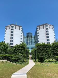two tall buildings in a park with a sidewalk at Hilton Paris Charles De Gaulle Airport in Roissy-en-France