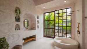 een badkamer met een groot bad en een groot raam bij Nick Villas by Villa Finder in Ubud