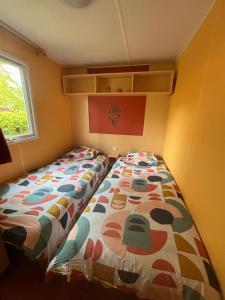 a bedroom with a bed with a colorful comforter at Mobilhome au bord du lac in Saint-Gérons