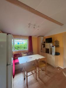 a kitchen with a table and a refrigerator in a room at Mobilhome au bord du lac in Saint-Gérons